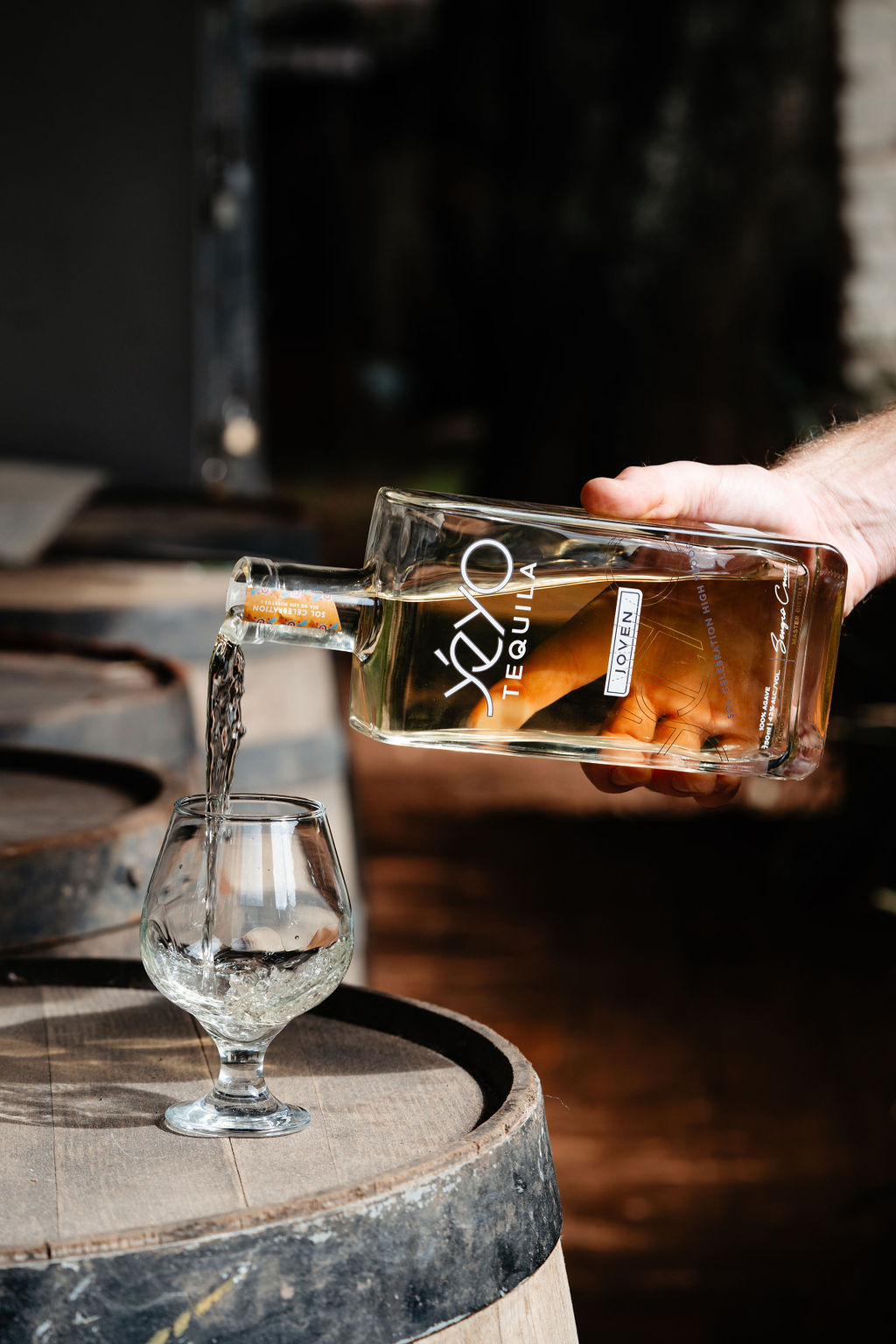 Yéyo Tequila Joven Sol being poured into a glass resting on a barrel