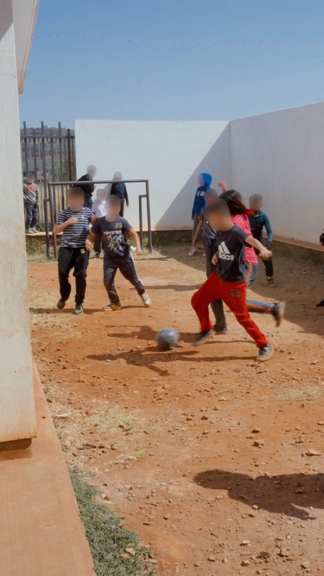 Children playing soccer in the dirt play area at Francisco Rojas Elementary School before Mission 1530 improvements
