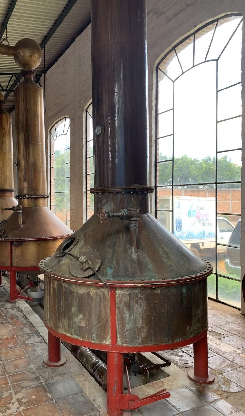 The Perfector, the weathered copper second still, beside arched windows at NOM 1414